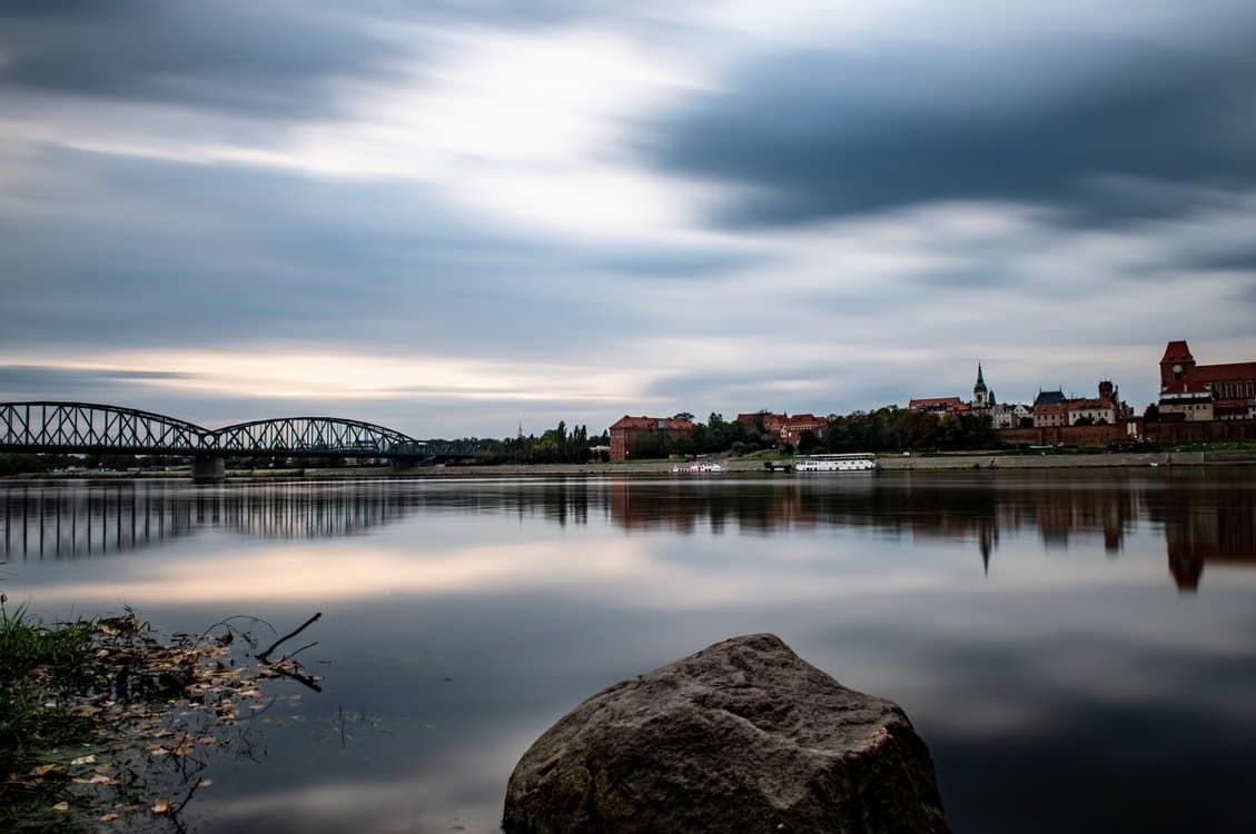 Wisła w pochmurny dzień. Na horyzoncie widać most oraz panoramę miasta.
